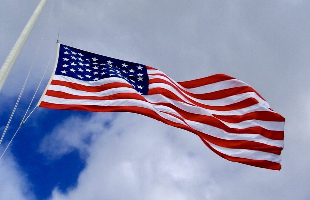 The American flag waves prominently against a partly cloudy sky.